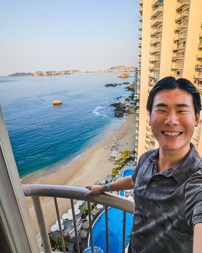 Travelling Foodie Raymond Cua smiling on a Hotel Amares balcony, enjoying stunning Acapulco beach and ocean views.