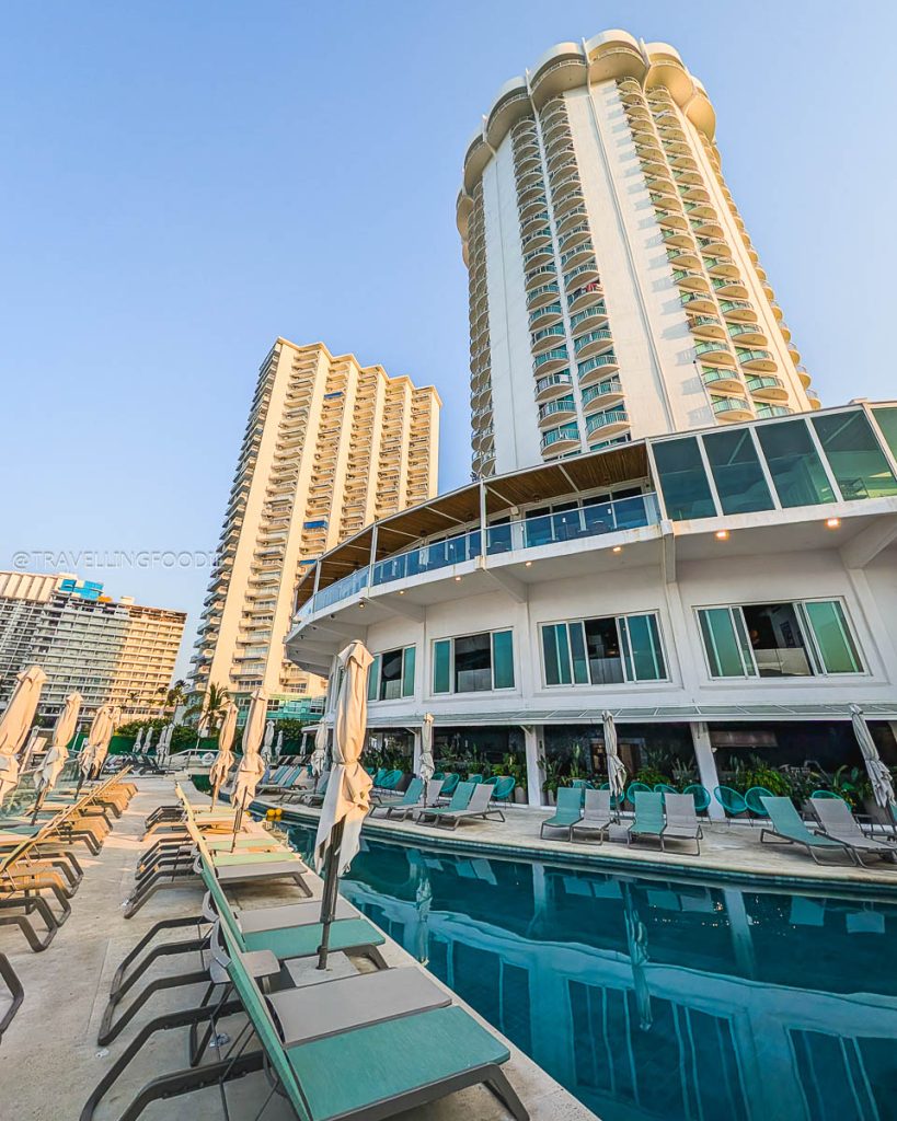 Exterior view of Hotel Amares towering over a beautiful swimming pool and lounge area, a great place to stay in Acapulco.