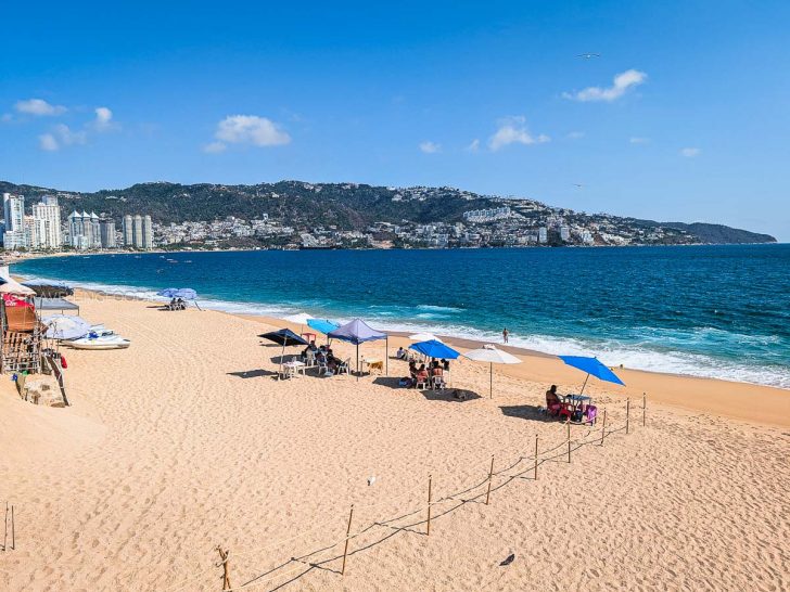 Scenic daytime view of Playa Icacos coastline in Acapulco, featuring blue ocean waters and distant mountain landscapes.