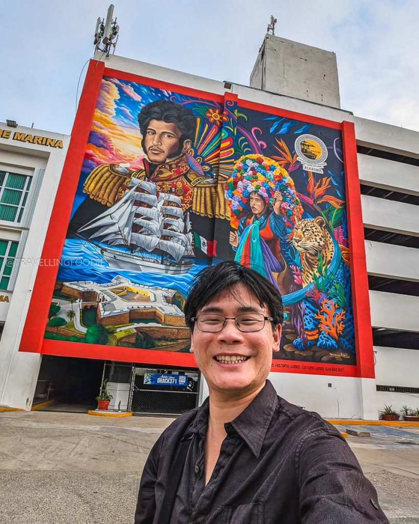 Raymond Cua taking a selfie with the massive Guerrero Náutico mural in Old Acapulco, a top historical attraction to visit.