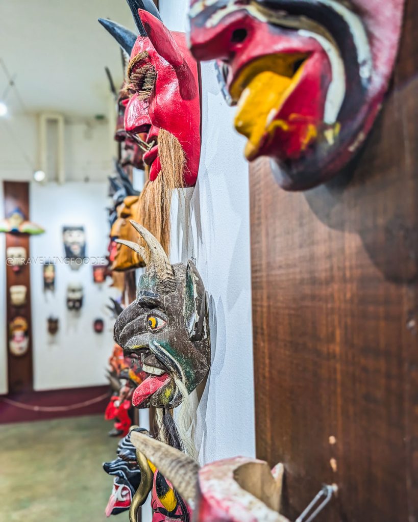 Collection of carved wooden devil masks hanging on a wall, showcasing local folklore at the Acapulco Mask Museum.
