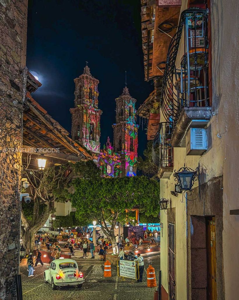 Santa Prisca church beautifully illuminated at night, viewed from a historic cobblestone street in Taxco de Alarcon.