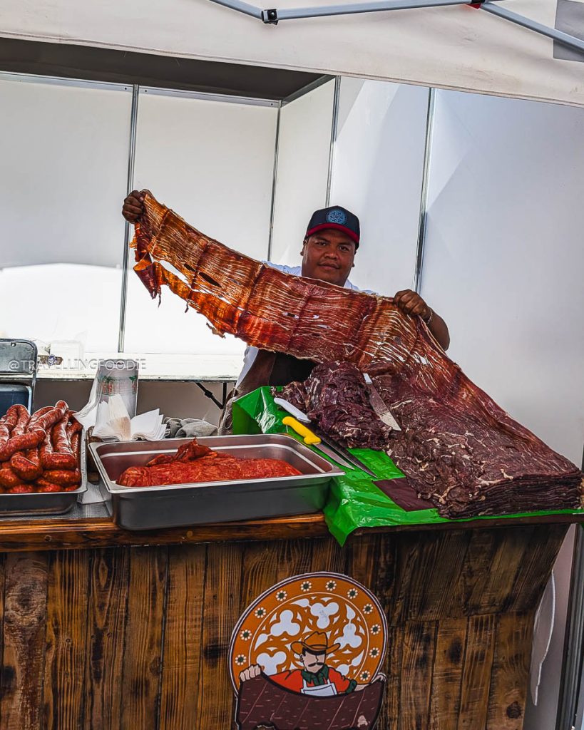 Morelos state vendor displaying massive sheets of traditional dried meat at the El Gran Taco festival during a Taxco day trip.