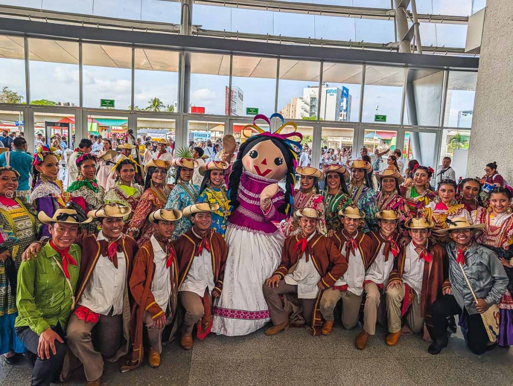 Performers in traditional Mexican attire and a large mascot at the Tianguis Turistico convention in Acapulco.