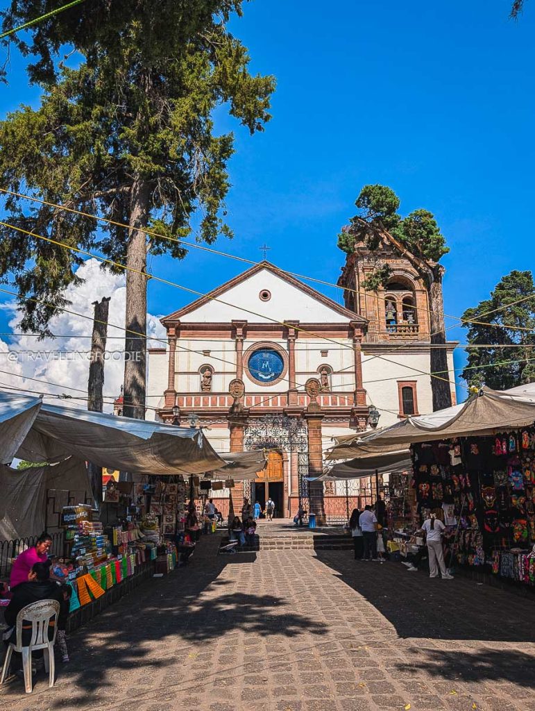 Vendor stalls outside Patzcuaro's Basilica of Our Lady of Health with trees growing on its bell tower.