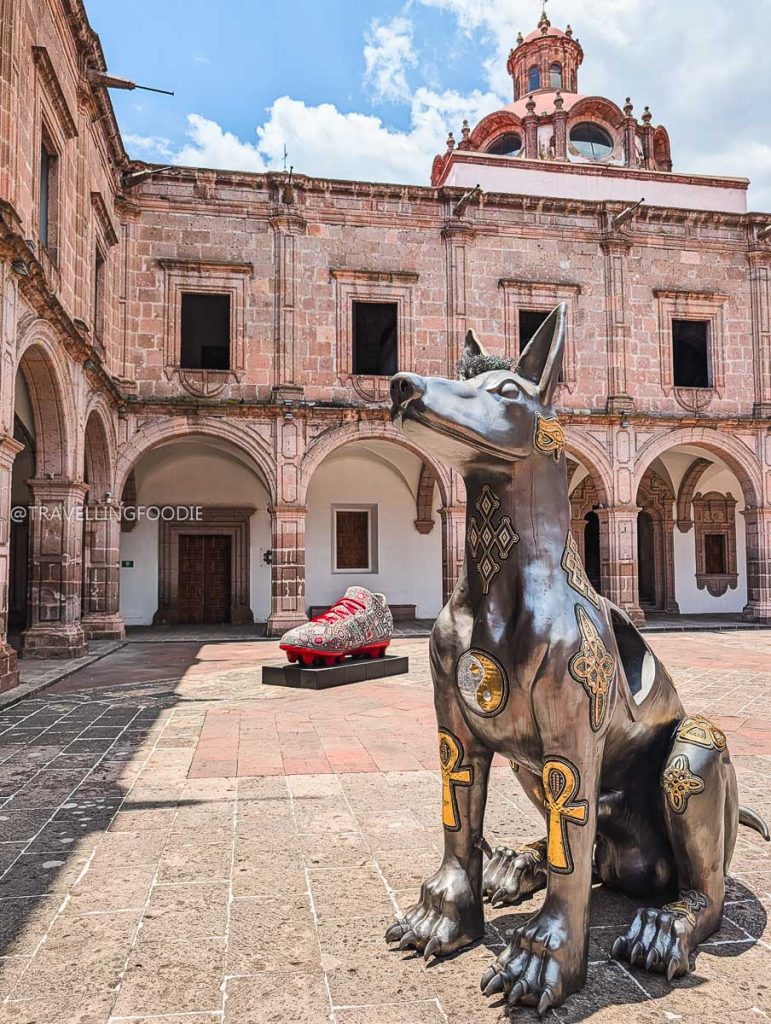 Detailed metallic dog sculpture on display in the pink stone courtyard of the Clavijero Cultural Center Morelia.