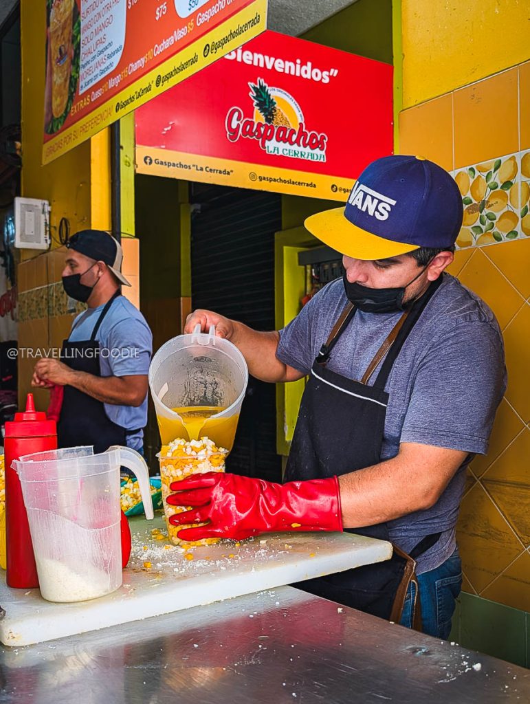 Vendor pouring fresh juice over Gaspacho Moreliano, some of the best food in Michoacan to try.
