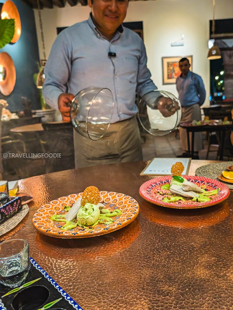 Waiter serving dessert with smoke under a cloche at Lu Cocina, one of the best restaurants in Michoacan.
