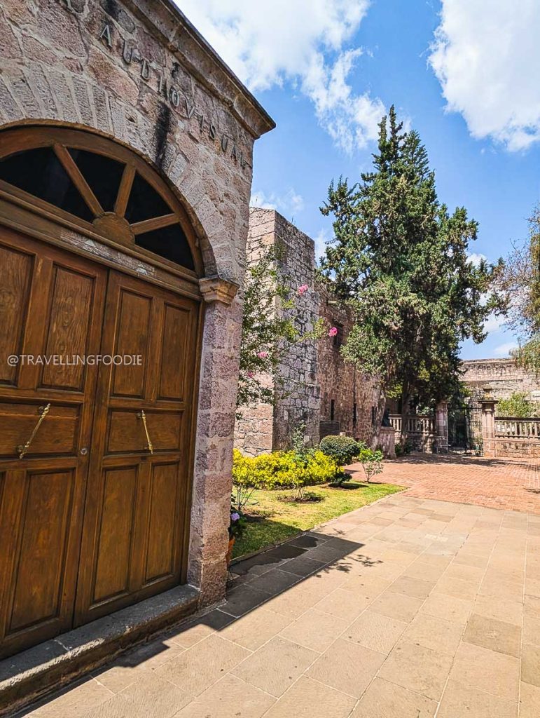 Historic wooden doors and courtyard at a colonial stone building to explore during a Michoacan trip.