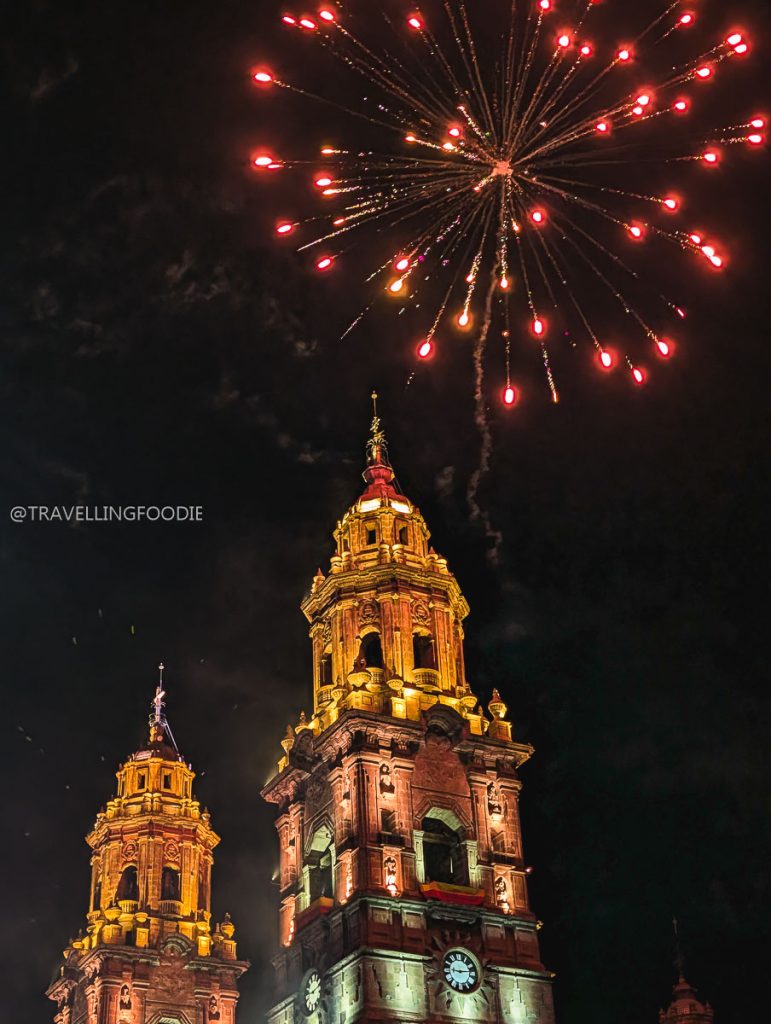 Red fireworks exploding over the illuminated towers of Morelia Cathedral on a Mexico vacation.