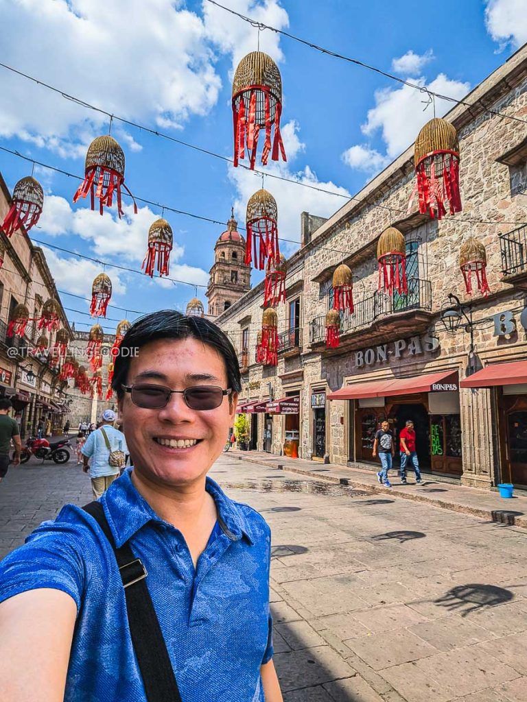 Travelling Foodie Raymond Cua smiling under decorative street lanterns during an unforgettable Mexico vacation in Morelia.