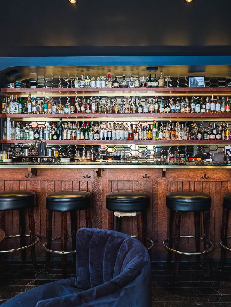 The beautifully stocked bar and cozy seating area inside Bar Ocelli, one of the best cocktail bars in Ottawa.