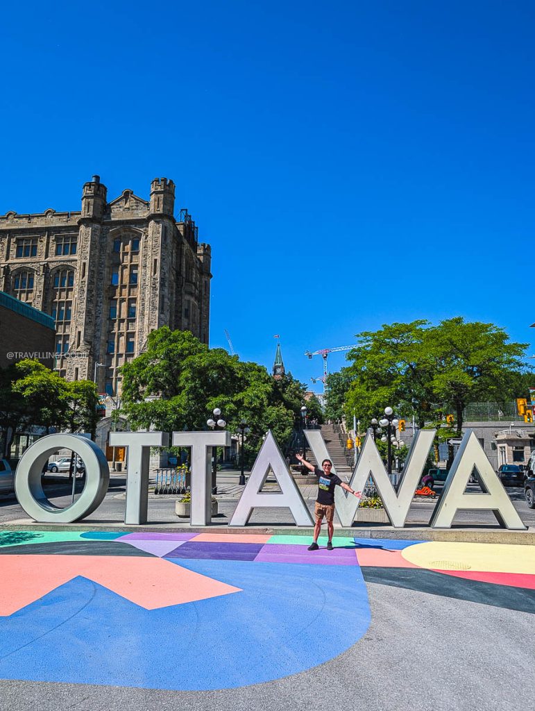 Travelling Foodie posing at the iconic Ottawa sign during an amazing culinary trip.
