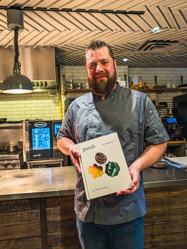 Chef Justin Champagne-Lagarde of Perch Ottawa restaurant holding his cookbook. Best places to eat food.