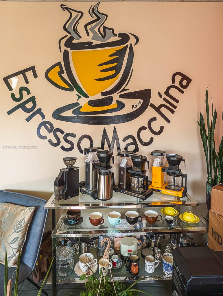 Coffee equipment display under the logo at Espresso Macchina, highlighting top local places to drink in Saskatoon.