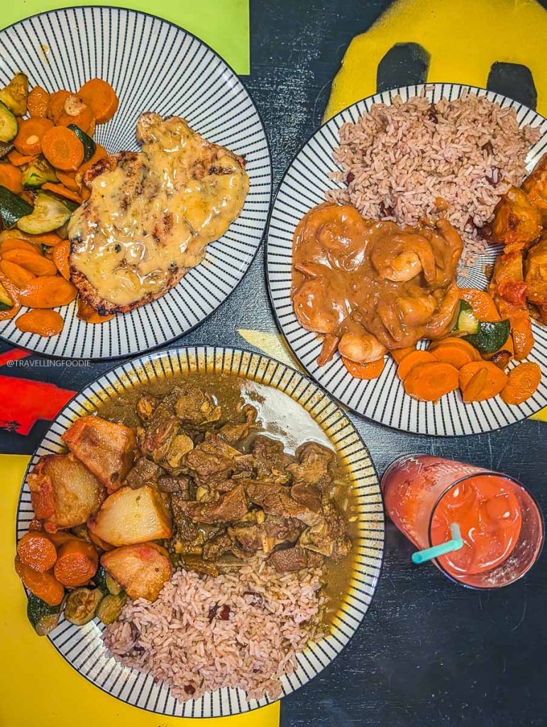 Plates of Curry Goat, jerk chicken, and spicy peanut shrimp at Konga Cafe, a top local restaurant in Saskatoon.
