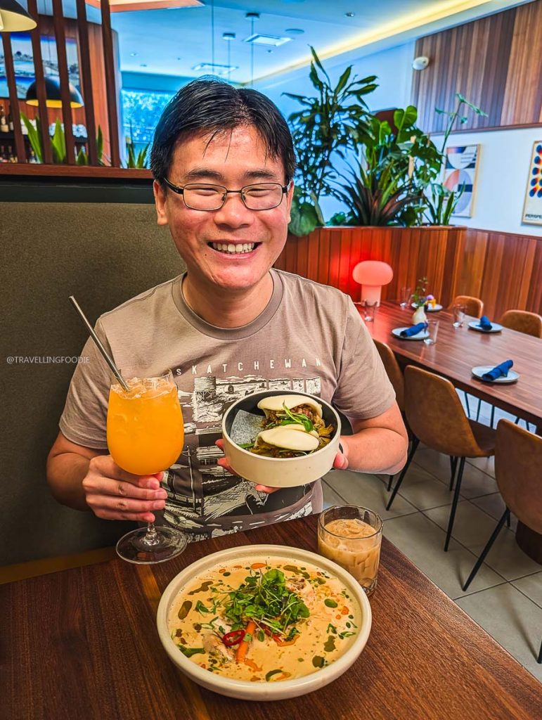 Raymond Cua holding Crispy Shrimp Bao at Loqui, showcasing amazing upscale Saskatoon food and cocktails.