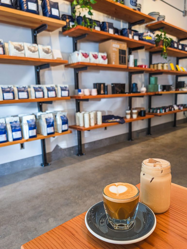 A warm cortado and iced coffee sitting on a table at The Colombian, highlighting top Saskatoon cafes.
