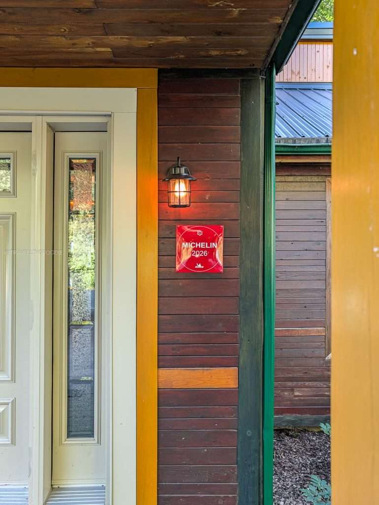 The red Michelin Guide 2026 plaque on the wooden exterior of Auberge Saint-Mathieu in Authentic Quebec.