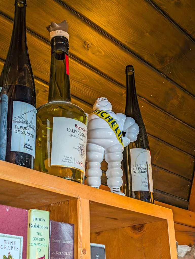 A vintage Michelin Man figure displayed on a wooden shelf beside wine bottles at Auberge Saint-Mathieu