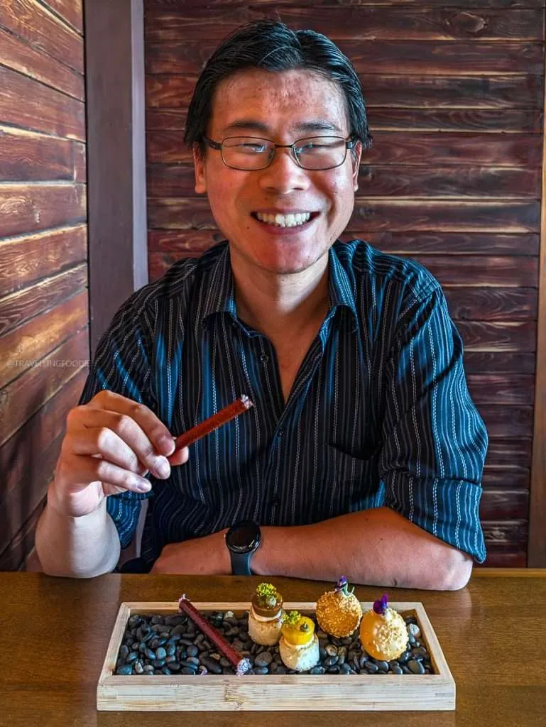 Raymond Cua eating a unique tomato cigarette with smoked halibut mousse during a Mauricie culinary road trip