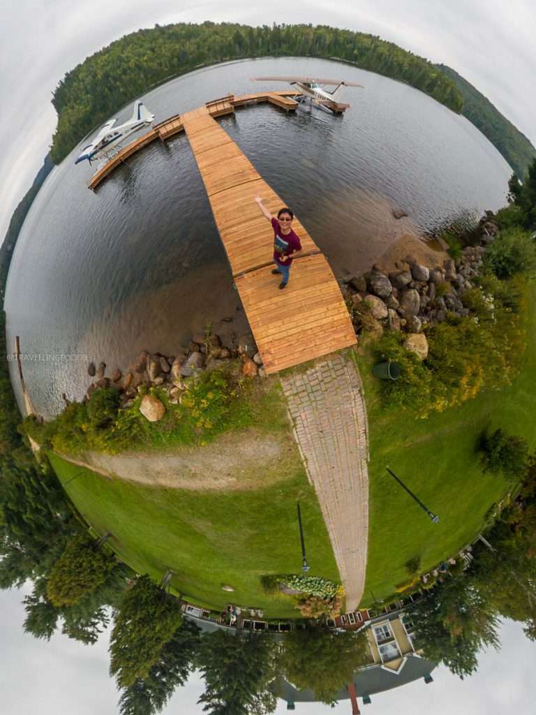Aerial view of me waving on a wooden dock with seaplanes at Auberge du Lac-a-l'Eau-Claire in Mauricie