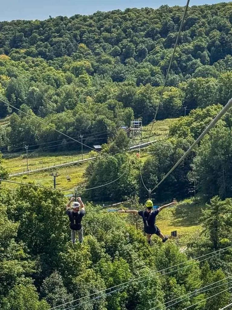 Raymond Cua and a friend soaring on the Peak to Peak zipline at Camp Fortune during a fun Chelsea Quebec trip.