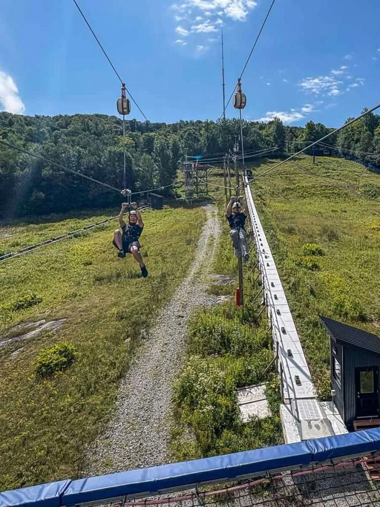 Raymond Cua and a friend riding dual ziplines side-by-side at Camp Fortune in Chelsea, Quebec.
