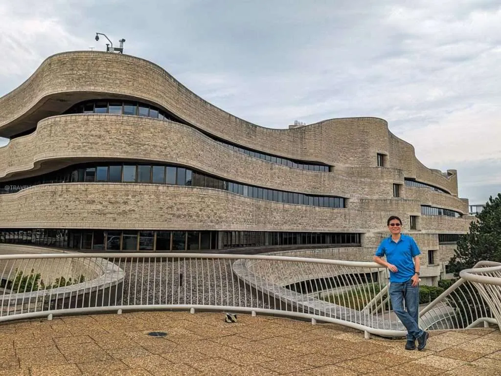 Raymond Cua standing beside the stunning undulating architecture of the Canadian Museum of History.