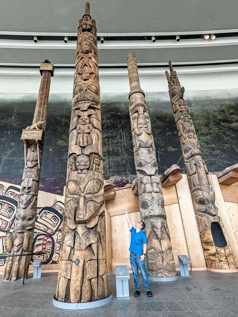 Raymond Cua looking up at massive wooden totem poles inside the Canadian Museum of History in Gatineau.