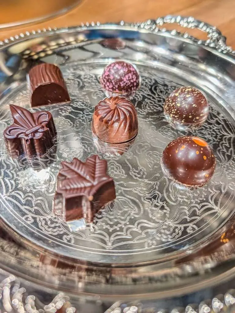 Handcrafted chocolate pralines shaped like a maple leaf and fleur de lis on a silver tray at ChocoMotive in Montebello.