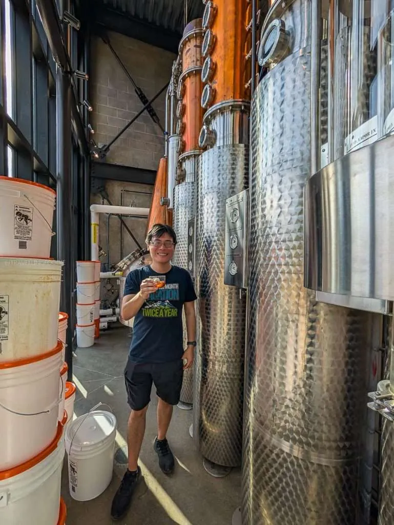 Raymond Cua holding a Bellagroni cocktail while touring the production floor at Distillerie du Square in Chelsea.