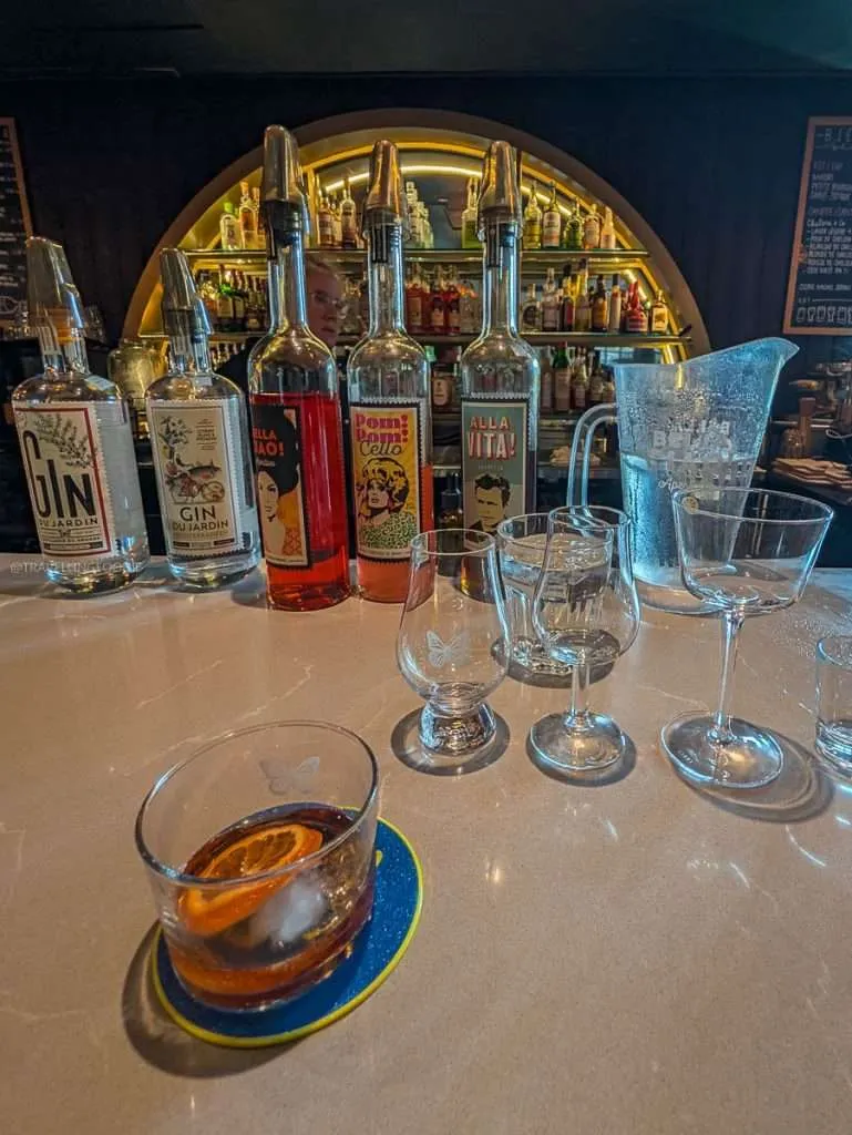 Craft spirit bottles and a fat-washed gin cocktail on the bar at Distillerie du Square, a top place to drink in Chelsea.