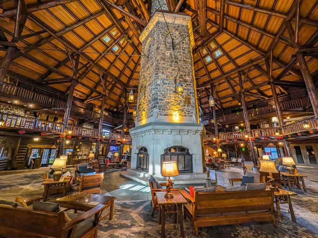The grand rustic lobby and iconic six-sided stone fireplace at the Fairmont Le Chateau Montebello log cabin resort.