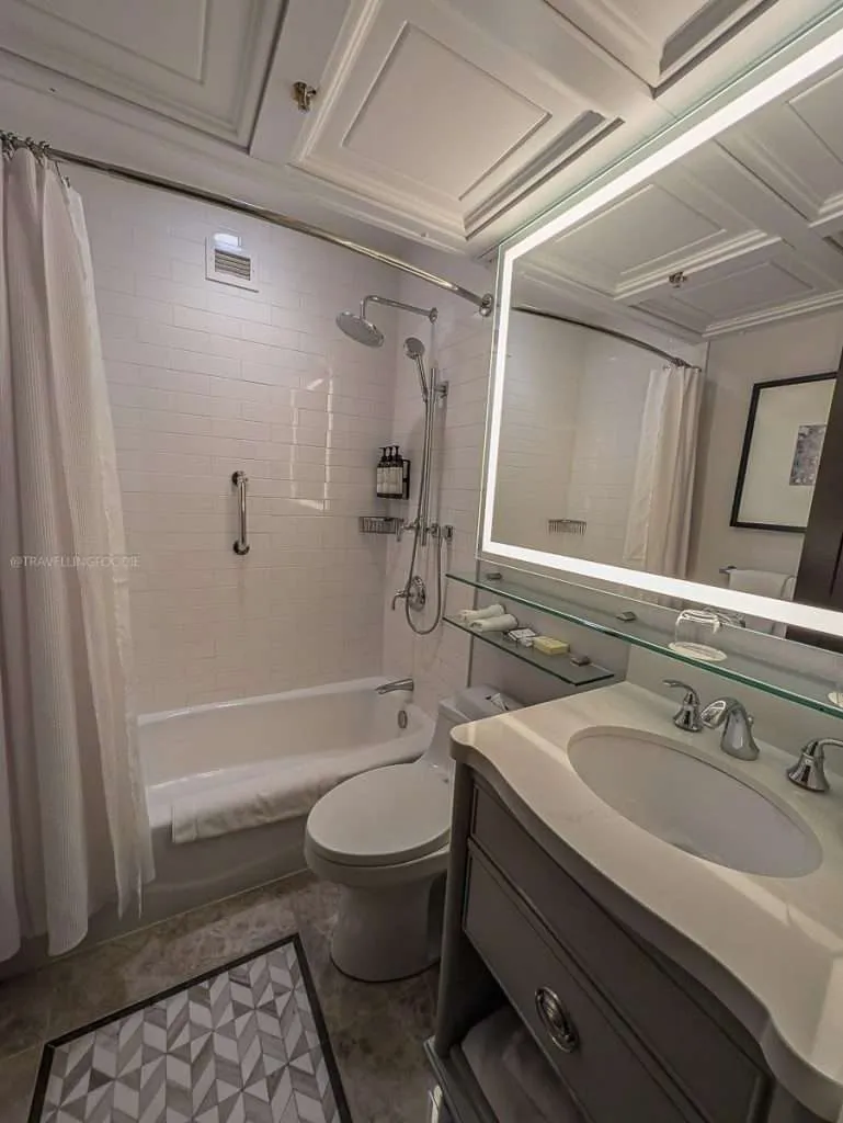 The modern white bathroom with a shower and lighted vanity at Fairmont Le Chateau Montebello.