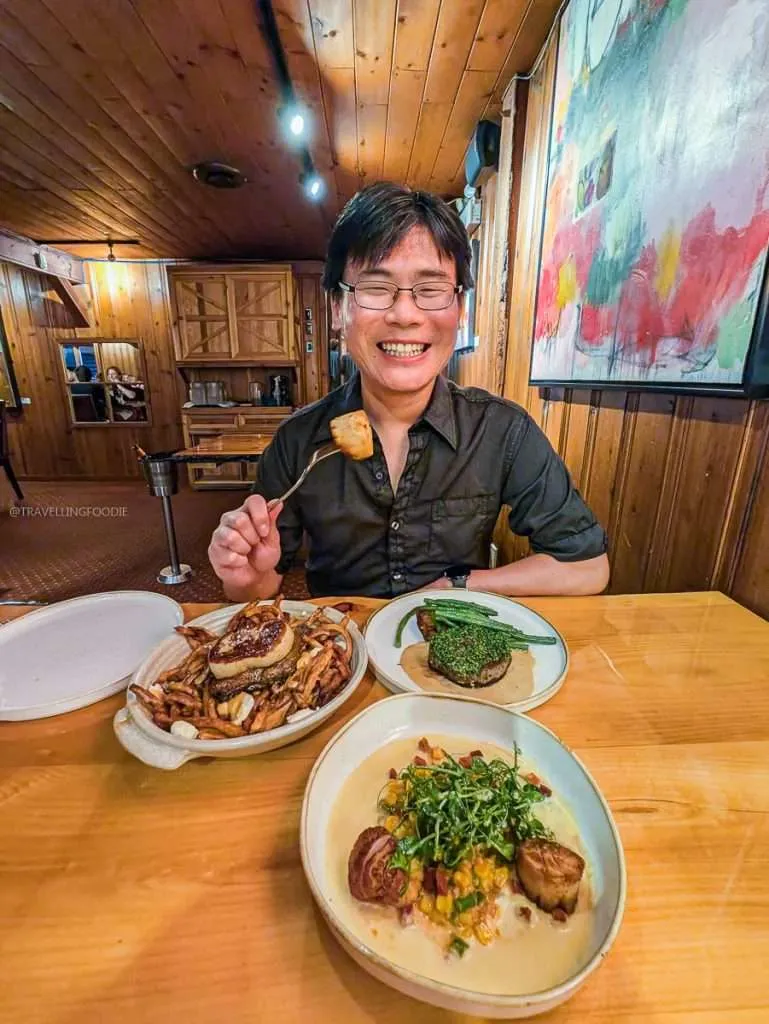 Travelling Foodie Raymond Cua eating pan-seared scallops and duck confit poutine at L'Oree du Bois restaurant in Chelsea Quebec.
