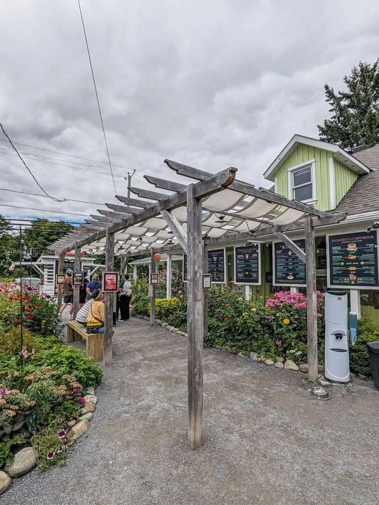 People lined up outside the beautiful garden entrance of La Cigale artisanal ice cream shop in Chelsea Quebec.