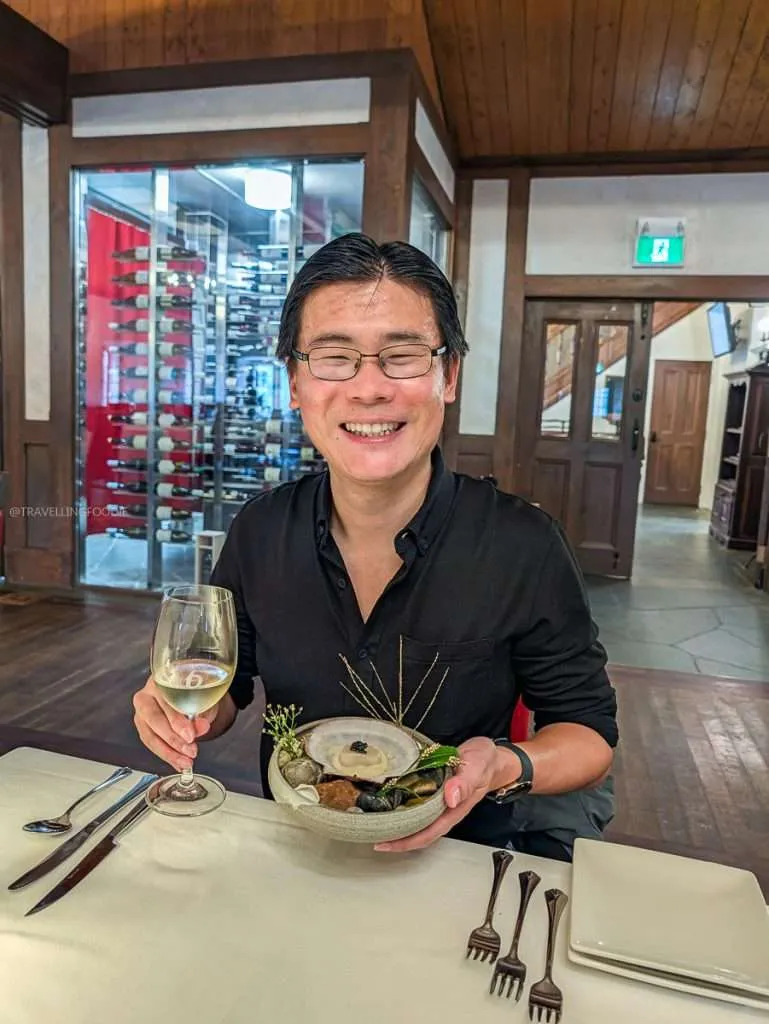 Travelling Foodie Raymond Cua smiling with a smoked scallop and caviar dish during the boreal tasting menu at Le Baluchon in Authentic Quebec