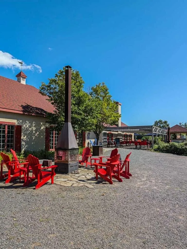 Red Adirondack chairs and a cozy fire pit outside at Le Baluchon eco-resort in the heart of Authentic Quebec