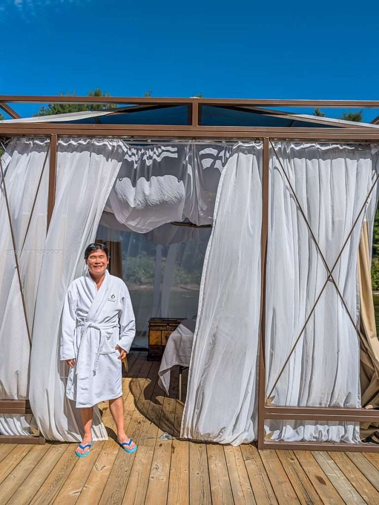Raymond Cua smiling in a cozy robe before the Massage by the Water at Le Baluchon in Lanaudiere-Mauricie.