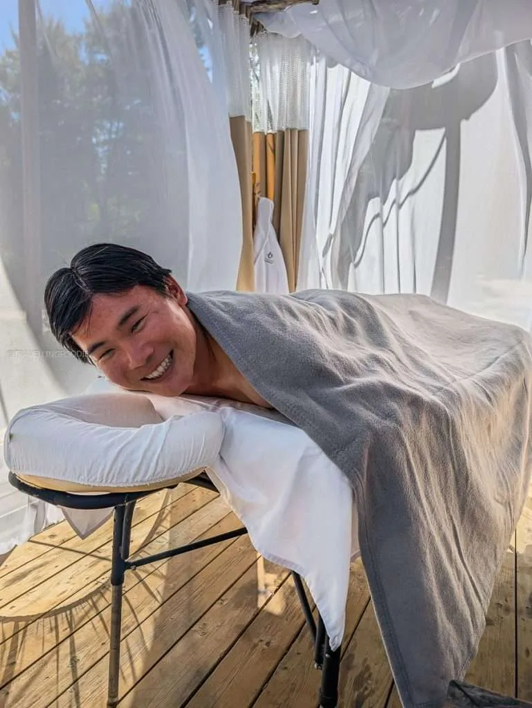 Raymond Cua smiling on the outdoor massage table by the river at Le Baluchon during our Authentic Quebec trip
