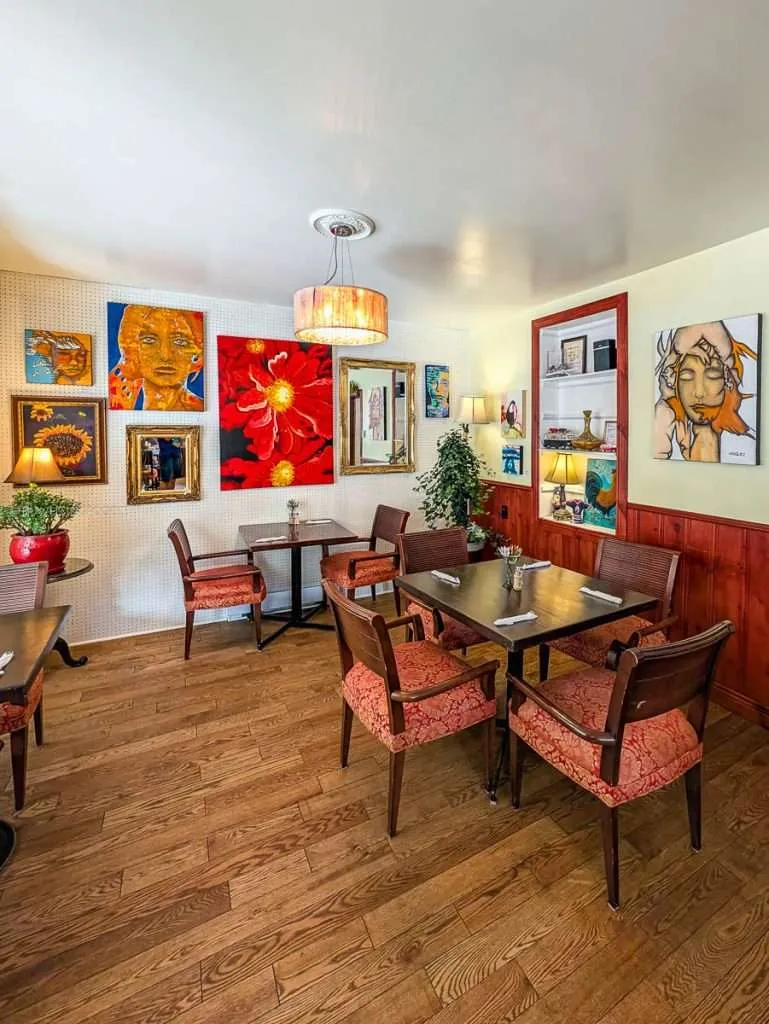 The cozy bistro dining room interior featuring colorful artwork on the walls at Le Cafe Entre Amis in Montebello Quebec.
