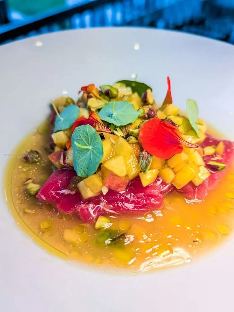 Colorful Gaspesian Bluefin Tuna Crudo with edible flowers at Les Fougeres, a top fine dining restaurant in Chelsea Quebec.