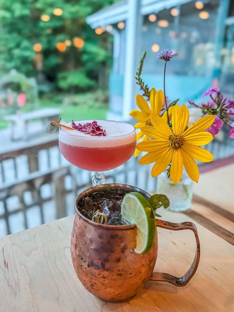 A pink Hibiscus Sour and Fougeres Mule cocktail on the outdoor patio at Les Fougeres, a must-visit Chelsea Quebec bar.
