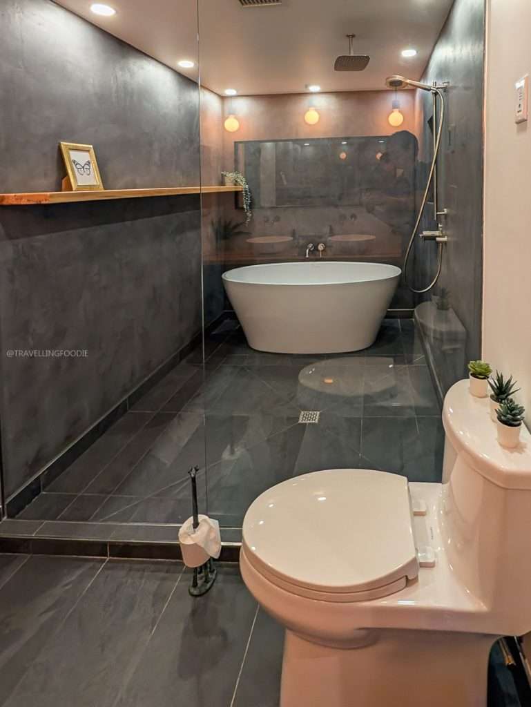 A modern luxury bathroom featuring a massive glass walk-in shower and deep soaking tub at Lofts du Village in Chelsea.