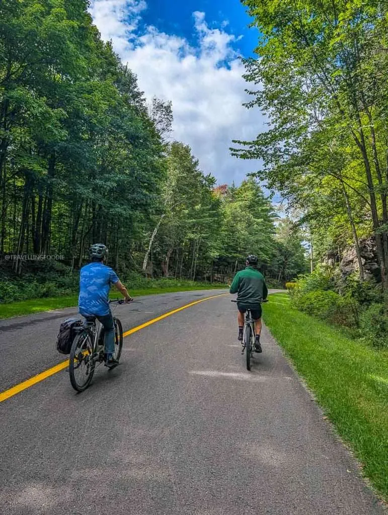 Raymond Cua and Vincent cycling along the car-free parkway on an e-bike tour in Gatineau Park near Chelsea, Quebec.