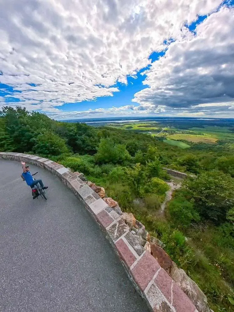 Raymond Cua waving while cycling along the scenic Eardley Escarpment in Gatineau Park near Chelsea.