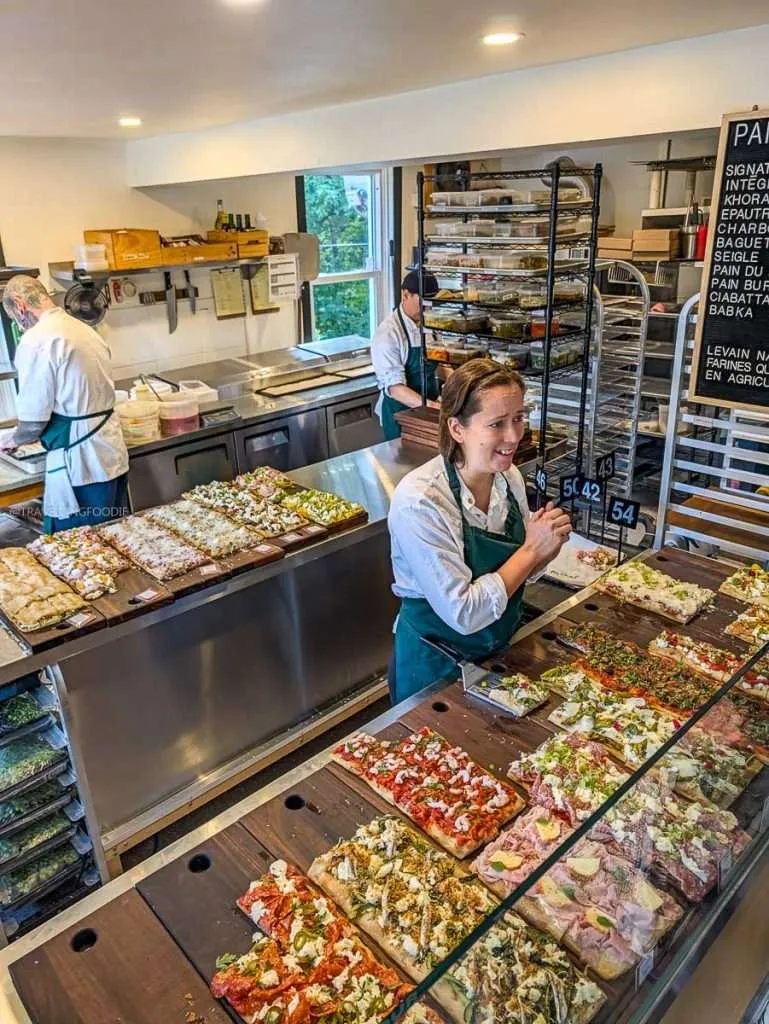 Display counter featuring Roman pizza al taglio slices and bakery staff at Roberto Pizza Romana in Chelsea Quebec